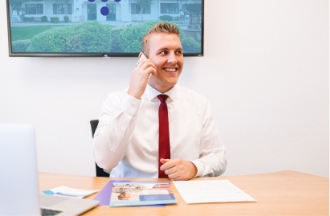 Business man in his office on the phone, smiling